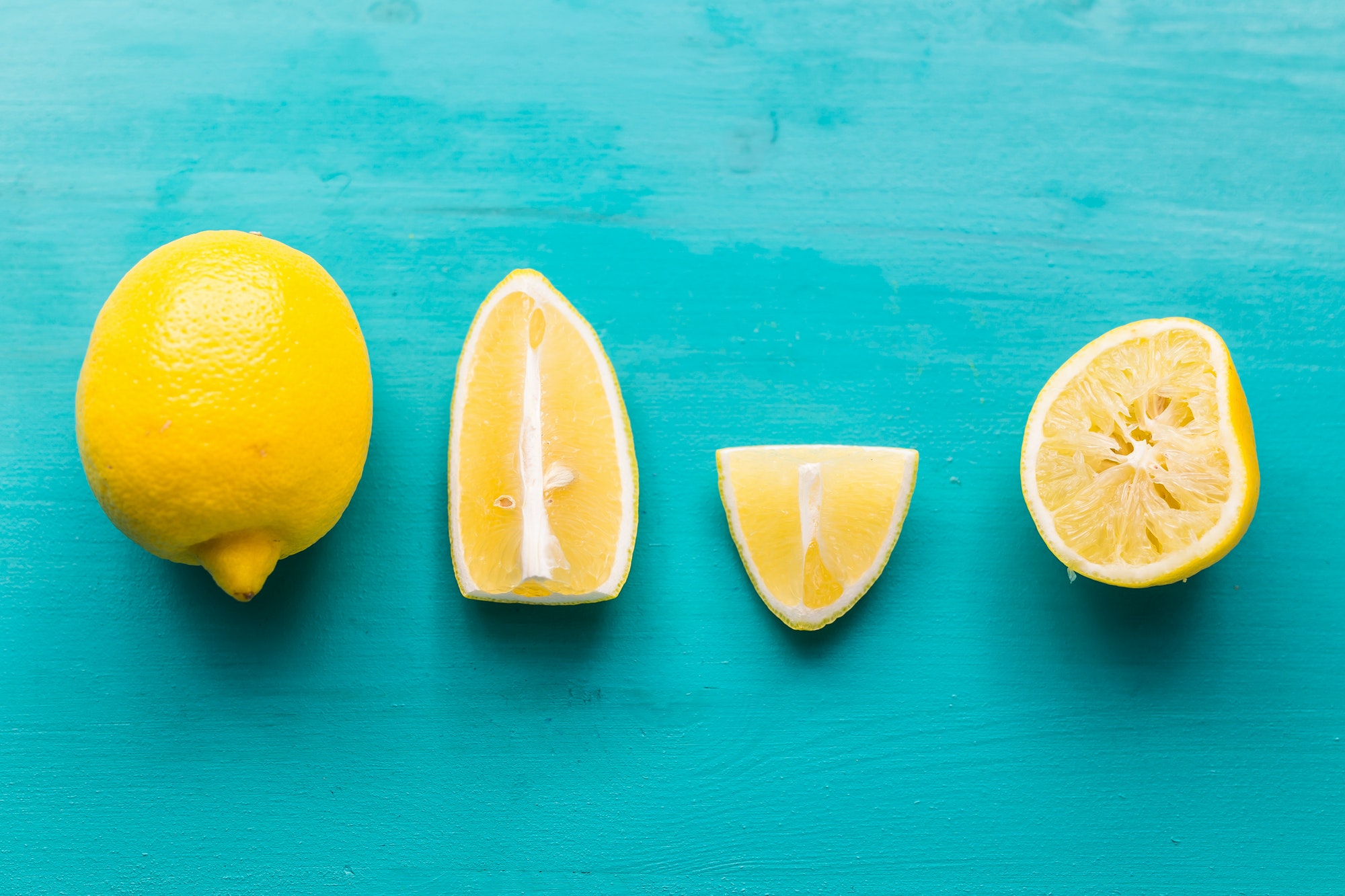 Freshly cut half and whole lemons on rustic aquamarine colour boards. Summer, vitamins and freshness